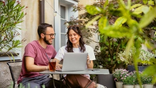 Studierende sitzen draussen in einem Kaffee, trinken etwas und arbeiten am Laptop.